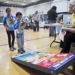 At the 2018 Back to School Fair, Charlie Petersen, 5, and Chelsea, 8, learn a bit about healthy living while playing a beanbag toss game at the Olympic Peninsula Healthy Community Coalition booth with help from volunteer Patty Shoop (right). Sequim Gazette file photo by Michael Dashiell