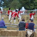 Left: The reenactors portraying the British Army fire on the Colonial Minutemen at the Battle of Concord Bridge while the crowd watches on during the Northwest Colonial Festivals portrayal.                                 Below: David Rieve, right, discusses Revolutionary War-era gunsmithing with several families in his tent at the Northwest Colonial Festival. Rieve, who is a trained gunsmith and has made numerous muskets and firearms that would be found in that era, has been coming to the Colonial Festival for several years and said that he enjoys the experience. Sequim Gazette photos by Conor Dowley
