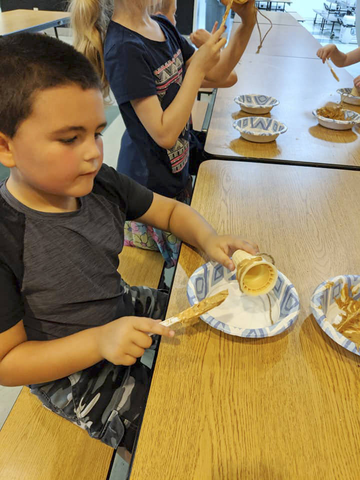 Morning camper Devin McBride works on a bird feeder made out of an ice cream cone rilled in peanut butter and bird seed. Submitted photo