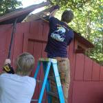 Eagle scout candidate Ian Thill, right, removes a section of the Pioneer Memorial Park storage sheds roof while Dylan Washburn, left, supports a larger section with a prybar. Washburn is an Eagle Scout himself and said that he wanted to lend his experience and support to his friend going through the same process. Sequim Gazette photo by Conor Dowley