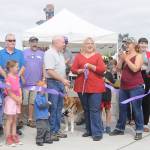 Gina Witz, Sequim Farmers Market board president (at center), cuts a ceremonial ribbon on at the market on Aug. 17, celebrating the markets designation as a nonprofit organization. Joining her are, among other dignitaries, Sequim Mayor Dennis Smith (center left). Sequim Gazette photo by Michael Dashiell