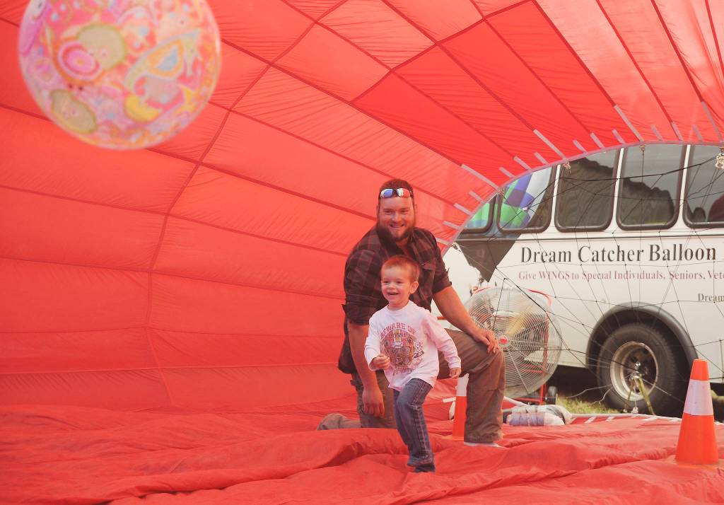 Lukas Cox watches as Camden Cox, 3, chases an inflated ball in the Morning Star Balloon Co.s bouncy balloon at the 2019 Olympic Peninsula Air Affaire and Sequim Valley Fly-in on Aug. 24.