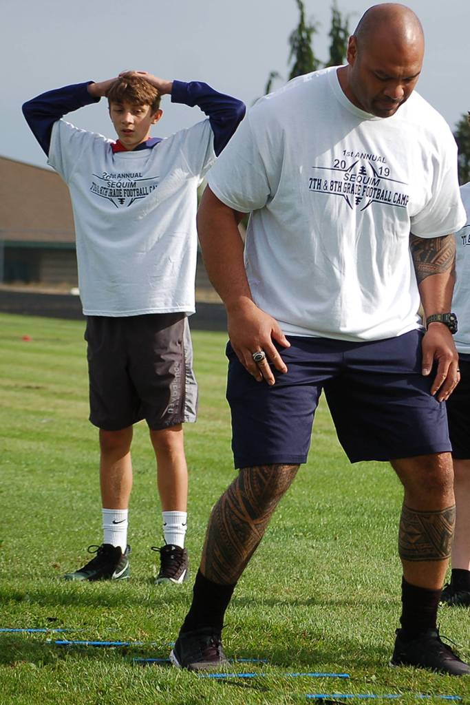 Sequim Middle School student Austin Schilling watches as Wayne Hunter, a former Seattle Seahawks offensive lineman who spent 11 years in the NFL, gives an example on how to properly run an agility ladder drill to a group of attendees of the first annual Sequim Middle School football camp. Sequim Gazette photo by Conor Dowley