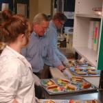 Chapman and Tharinger serve lunches while the clubs kitchen coordinator Bree Daniels, left, waits to hand them more plates of food to pass out. The representatives handed out more than 120 meals.