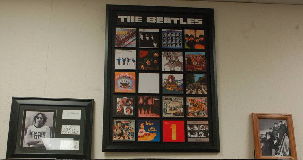 A framed collection of Beatles covers, along with autographs from John Lennon and a picture of The Beatles leaving for the United States for a landmark tour in 1964. Upper right inset, a collectable lunchbox, a fan club magazine, and a pin are among the items celebrating The Beatles on display at KSQM. Collection owner George Dooley said that the sheer scale of collectible items around the band was astounding, including things like the tie pins in the collection that quickly became difficult to find. Sequim Gazette photos by Conor Dowley