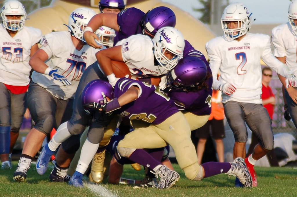 Several Sequim Wolves defenders converge on Washington Patriots running back Malachi Walker in the first quarter of the Wolves non-league 42-14 win over Washington on Sept. 6. Sequim Gazette photo by Conor Dowley