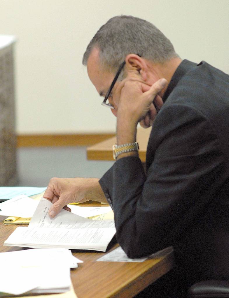 William Payne, attorney for Olympic Medical Center Commissioner District 1 candidate Ann Marie Henninger, examines court papers during Henningers hearing on Thursday contesting her eligibility for the seat. Photo by Keith Thorpe/Peninsula Daily News