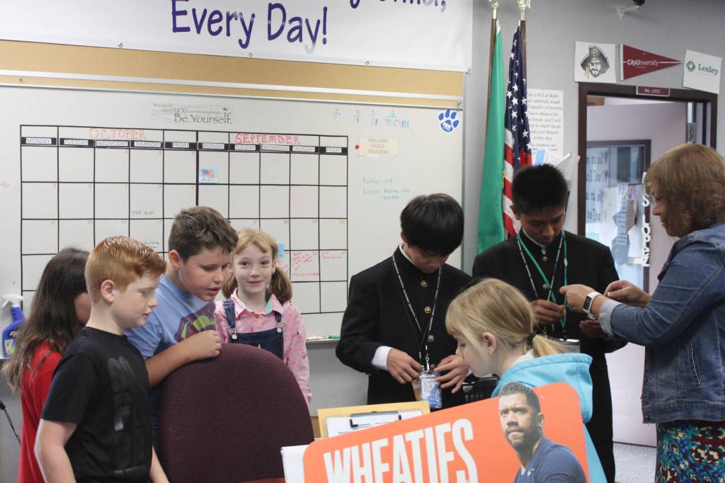 From left, Greywolf Elementary students Kaitlyn Carpenter, Sawyer Tomco, Noah Green and Rebecca Marshal and staffer Tricia Stratton teach Shiso City Ambassadors about the schools CARES (Cooperation, Attitude, Respect, Effort & Safety) program by presenting them with colorful plastic paw charms during the ambassadors visit in September. Photo by Donna Hudson