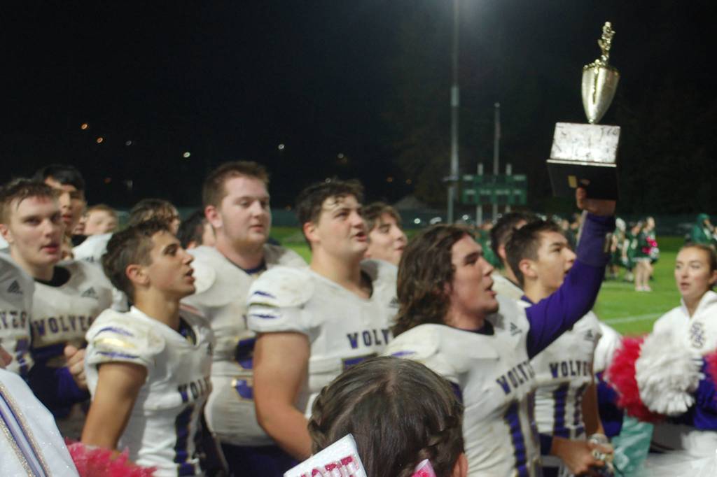 Taig Wiker holds the Rainshadow Rumble trophy up high as the Sequim Wolves celebrate their 26-0 win over Port Angeles Roughriders on Oct. 18 with the fans who traveled to Civic Field to cheer them on. The win was Sequims fifth straight in the series, and Wiker ran for two touchdowns and threw for another in the game. Sequim Gazette photo by Conor Dowley