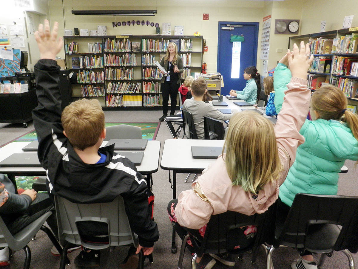 As teacher-librarian Sheri Kruckeberg reviews earthquake drill procedures, fourth-graders from Jaysa Hills class at Helen Haller Elementary School ask questions in anticipation of the Great Washington Shake Out. The drill was scheduled to take place during their library time on Oct. 17. Below, Fourth-graders at Halen Haller Elementary School take cover under library tables as Great Washington Shake Out earthquake drill begins. Photos by Patsene Dashiell