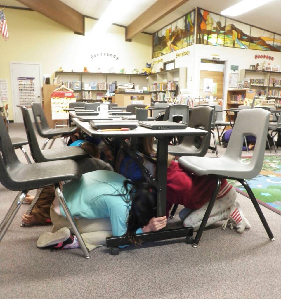 Fourth-graders at Halen Haller Elementary School take cover under library tables as Great Washington Shake Out earthquake drill begins. Photo by Patsene Dashiell