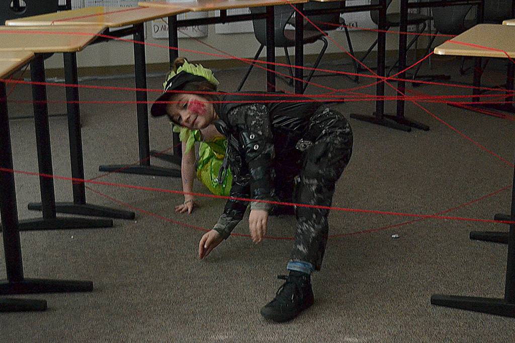 SWAT team member Alivia Cummings, 7, makes her way through the laser (yarn) course with her sister Aria, 4, as Tinkerbell behind her. Sequim Highs senior class made the course and rewarded those who complete it with candy at Haunted Hallways on Oct. 26. Sequim Gazette photo by Matthew Nash