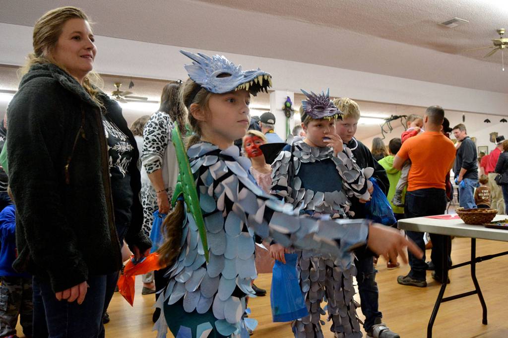 Sydney Blackburn, 8, takes a throw at the You dirty Rat game as her twin brother Nicholas and mom Nicole watch at the Sequim Prairie Granges Country Fair. The siblings went as an ice dragon and midnight dragon, Sydney said. Sequim Gazette photo by Matthew Nash