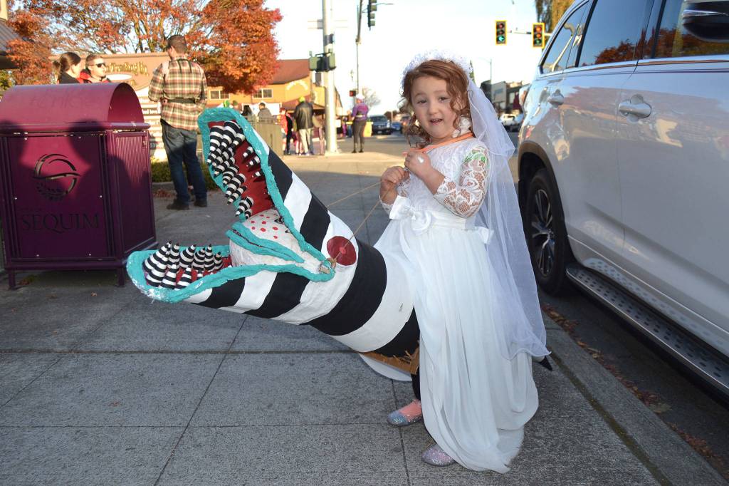 Lyric Koester, 4, of Agnew takes a ride as Delia Deetz on a sandworm from the movie Beetlejuice in downtown Sequim during Halloween. Lyrics parents said the sandworm was made of paper mache. Sequim Gazette photo by Matthew Nash