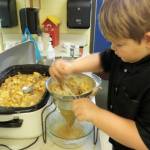Second-grader Liam Bower processes cooked apple pieces through a food mill to make delicious applesauce in Renee Mullikins classroom. The apples were provided by Clallam Gleaner Kathy Strozyk. Photo by Patsene Dashiell
