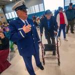 Richard Fleck of the Coast Guard Auxillary finds a seat for Navy veteran Frank Meek, who served during World War II, during the Veterans Day ceremony at U.S. Coast Guard Air Station/Sector Field Office Port Angeles on Monday. (Jesse Major/Peninsula Daily News)