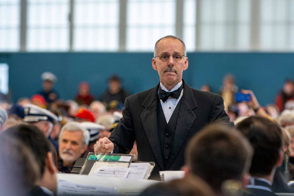 Doug Gailey directs the Port Angeles High School Band during the Veterans Day ceremony at U.S. Coast Guard Air Station/Sector Field Office Port Angeles on Monday. (Jesse Major/Peninsula Daily News)