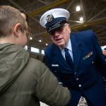 Richard Fleck of the Coast Guard Auxillary welcomes a young boy to the Veterans Day ceremony at U.S. Coast Guard Air Station/Sector Field Office Port Angeles on Monday. (Jesse Major/Peninsula Daily News)