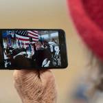 A woman records video of Members of the Mount Olympus Detachment of the Marine Corps League perform a three-volley rifle salute at the Veterans Day ceremony at U.S. Coast Guard Air Station/Sector Field Office Port Angeles on Monday. (Jesse Major/Peninsula Daily News)