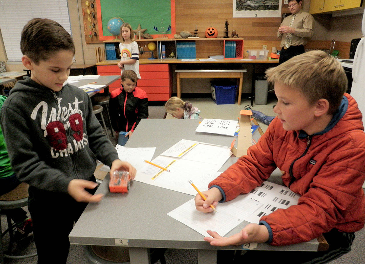 Working as a team, Joshua Wakefield, left, and Daniel Colwill, fourth-graders in Jesse Klingers class at Helen Haller Elementary, make their Edison Robot turn on, move forward and stop during a recent lesson. Photo by Patsene Dashiell