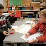 Working as a team, Joshua Wakefield, left, and Daniel Colwill, fourth-graders in Jesse Klingers class at Helen Haller Elementary, make their Edison Robot turn on, move forward and stop during a recent lesson. Photo by Patsene Dashiell