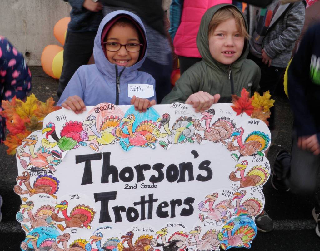 Second-graders Faith Eaton and Brodie Chatski proudly display their class sign at the beginning of Helen Haller Elementarys Turkey Trot on Nov. 27. Photo by Patsene Dashiell