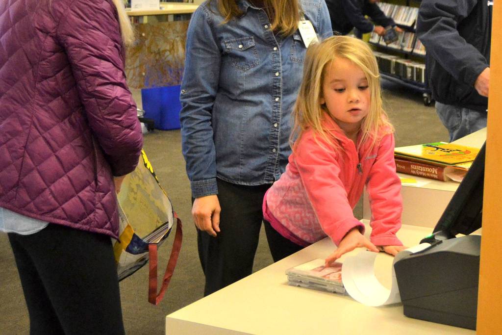 Aubrie Huisman, 4, helps her grandmother Rachel McKay at the Sequim Library by grabbing her receipt for books they checked out as McKay speaks with Emily Sly, Sequim Library branch manager. In January, library trustees discuss possible funding to reconfigure the Sequim Library to make more room for operations. Sequim Gazette photo by Matthew Nash