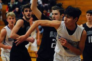 Freshman forward Isaiah Moore, second from right, passes the ball out from under the basket while under pressure from Klahowya Eagles forward Deven Patch during the Sequim Wolves 45-37 win over the Eagles on Dec. 2. Moore had eight points, eight rebounds and two blocks in his first high school game. Sequim Gazette photo by Conor Dowley