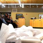 A pile of petition papers sit below a table as Jodi Wilke, spokesperson for Save Our Sequim, speaks on Dec. 9 about the groups beliefs and research that a proposed medication-assisted treatment facility would negatively impact Sequim. Sequim Gazette photo by Matthew Nash