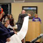 During public comments at the Dec. 9 Sequim city council meeting, members of Save Our Sequim (SOS), Cheryl Cuccia and George Noa unrolled 2,600 signatures SOS members collected in recent months asking Sequim city councilors to oppose placing the proposed medication-assisted treatment facility in Sequim. Jodi Wilke, on right, said the clinic would add costs for medical, housing, and law enforcement expenses to the public. Sequim Gazette photo by Matthew Nash