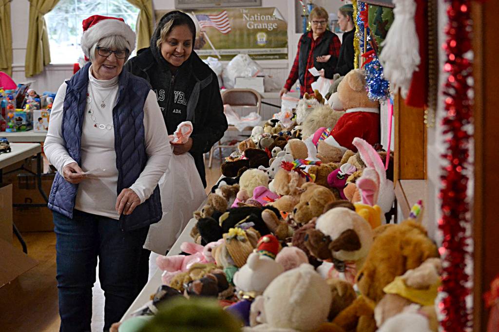 Nancy Garbush helps Karena Mora find stuffed animals for her three children ages 7, 12 and 14 at Toys for Sequim Kids. Below, friends, from left, Sisa Morrill, Emma Menes and Farah Durham stand together after attending Toys for Sequim Kids on Dec. 11. The three moms received toys, games and more for their six children ranging from 4-12 through Sequim Community Aid. Menes said they came last year and the event helps them a lot. Sequim Gazette photos by Matthew Nash
