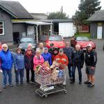 Volunteer Stephen Rosales, far right, accepts an annual monetary and food donation from the The Olympic Peninsula Chapter of Club Miata Northwest on Dec. 12 for the Sequim Food Bank. Sequim Gazette photo by Matthew Nash