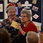 Nancy McGovern, president of the Sequim-Dungeness Hospital Guild, on left, honors Randi Cooper, thrift shop chairman of donations, during the guilds volunteer luncheon on Dec. 12 in St. Lukes Episcopal Church. Cooper said part of her job is checking items and prices. Sequim Gazette photo by Matthew Nash