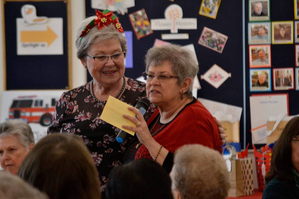 Nancy McGovern, president of the Sequim-Dungeness Hospital Guild, on left, honors Randi Cooper, thrift shop chairman of donations, during the guilds volunteer luncheon on Dec. 12 in St. Lukes Episcopal Church. Cooper said part of her job is checking items and prices. Sequim Gazette photo by Matthew Nash