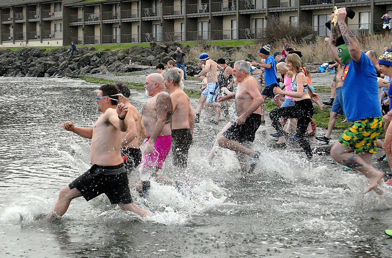 Polar Bear Dip participants race into the chilly waters at Port Angeles Harbors Hollywood Beach on New Years Day in 2019. File photo by Keith Thorpe/Olympic Peninsula News Group