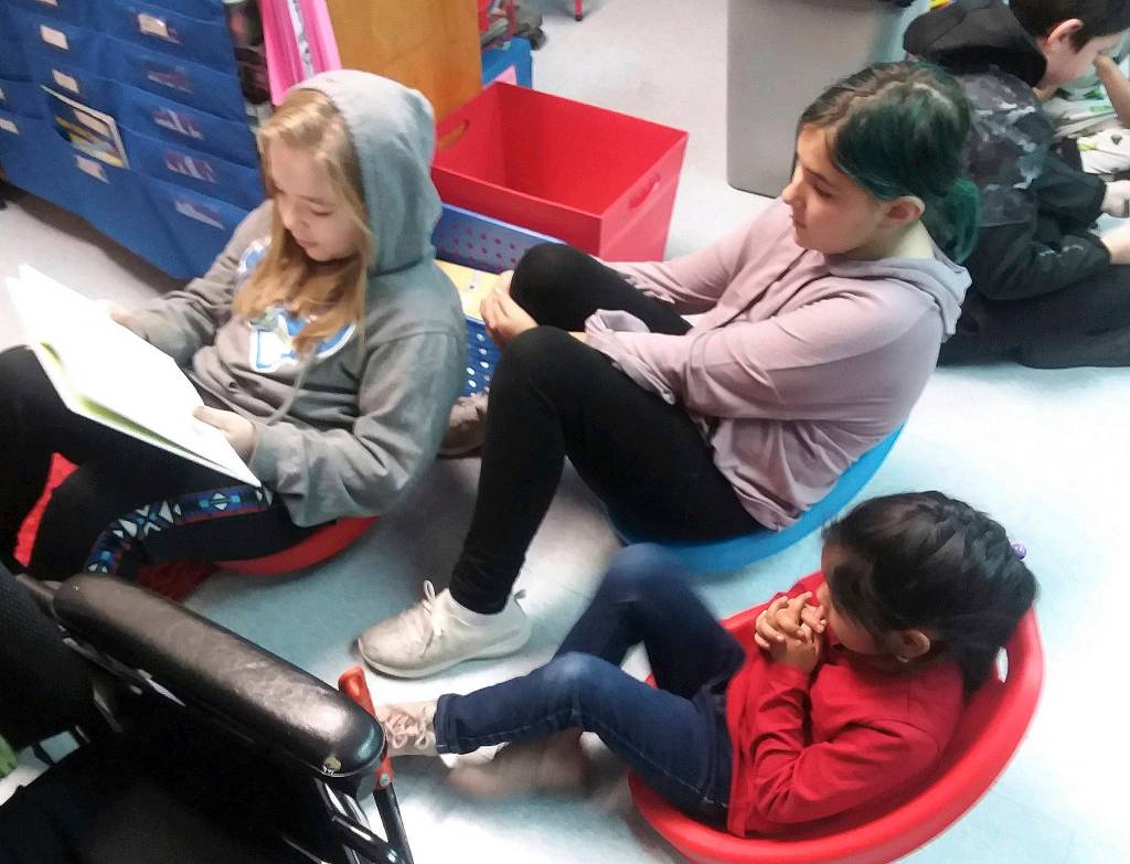 From left, fifth-graders Leila Sanderson and Lucy Vincent read to first-grader Eulalia Gonzalez. Photo by Patsene Dashiell