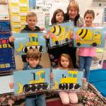First-graders from Christine MacDougall Danielsons class create artwork inspired by the Fir Street construction project to make placemats for school board directors. Pictured are (back row, from left) Aden Uhlig, Corinne Piersoll, MacDougall Danielson and Fenja Johnson, with (front row, from left) Makai Garten and Evelyn Moose. Photo by Patsene Dashiell