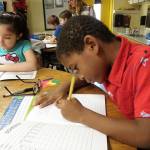 Second-graders Camren Williams, right, and Michelle Marquez get to work on their writing task.