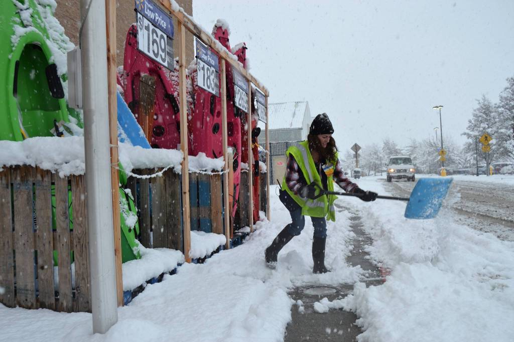 Jeni Madsen, manager of boys and men clothing at Sequim Walmart, helps shovel a pathway on Feb. 8 as snow begin to blanket the area. Sequim Gazette file photo by Matthew Nash
