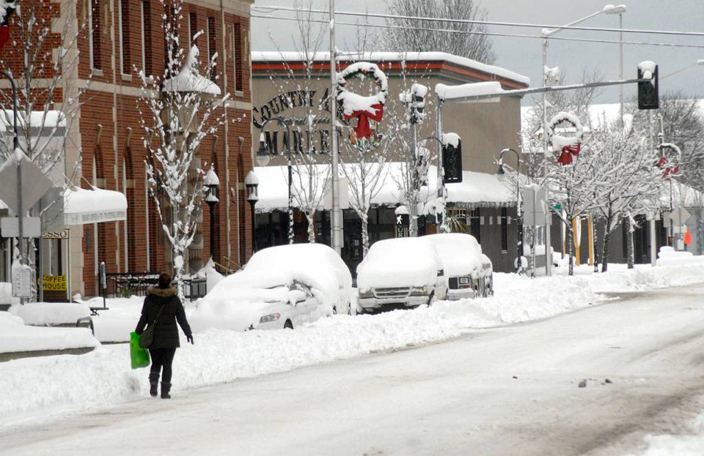 A pedestrian makes her way along a snow-covered Front Street in downtown Port Angeles on Wednesday after heavy snow blanketed the city overnight. Photo by Keith Thorpe/Olympic Peninsula News Group