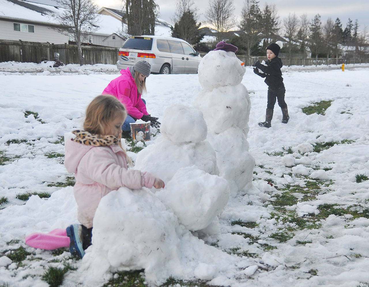 Cheyeanne Cooper helps out as Annyah Beck, 4, and Kayden Beck, 6, work on snow figures near downtown Sequim on Jan. 16. Sequim Gazette photo by Michael Dashiell