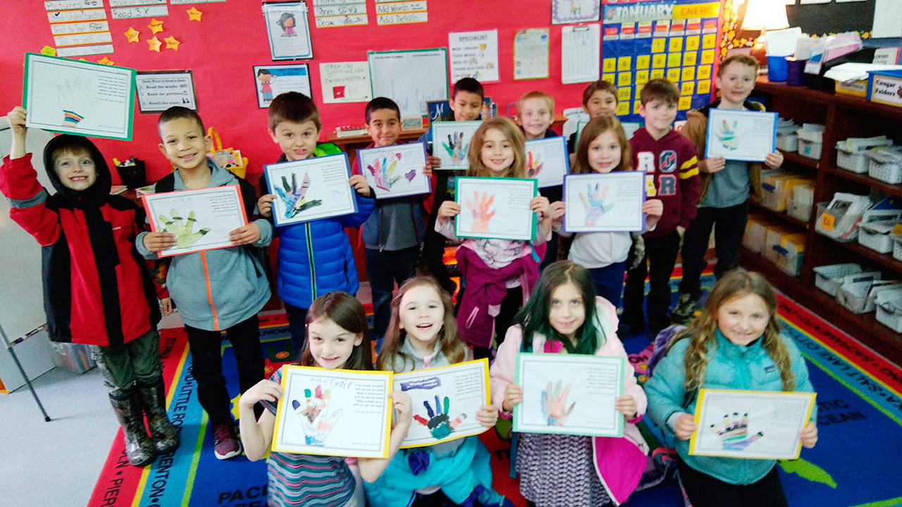 Students in Ione Marcys first-grade class show their completed project of a tracing of their hand painted with multiple colors. Photo by Ione Marcy