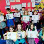 Students in Ione Marcys first-grade class show their completed project of a tracing of their hand painted with multiple colors. Photo by Ione Marcy