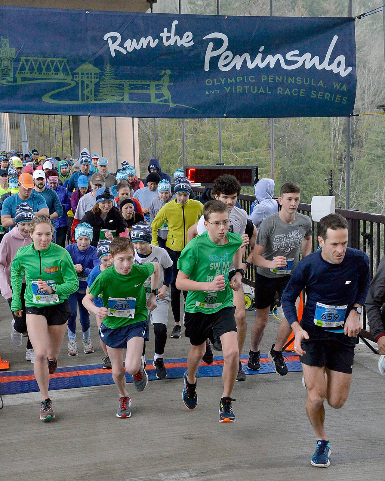 Runners cross the starting line during the Elwha Bridge 5K/10K Run, the first race in the second annual Run the Peninsula series, on Feb. 1. Womens 10K winner Lauren Larson of Port Angeles is at far left, while male 5K winner Colby Ellefson of Sequim and male 10K winner John Mauro of Port Townsend are at right. EnMotive Photography