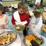Third-graders (from left) McKenna Cox, Blake Arnold and Xyla Reichner prepare to feast on ancient Roman foods at the conclusion of their study unit. Photo by Robin Forrest