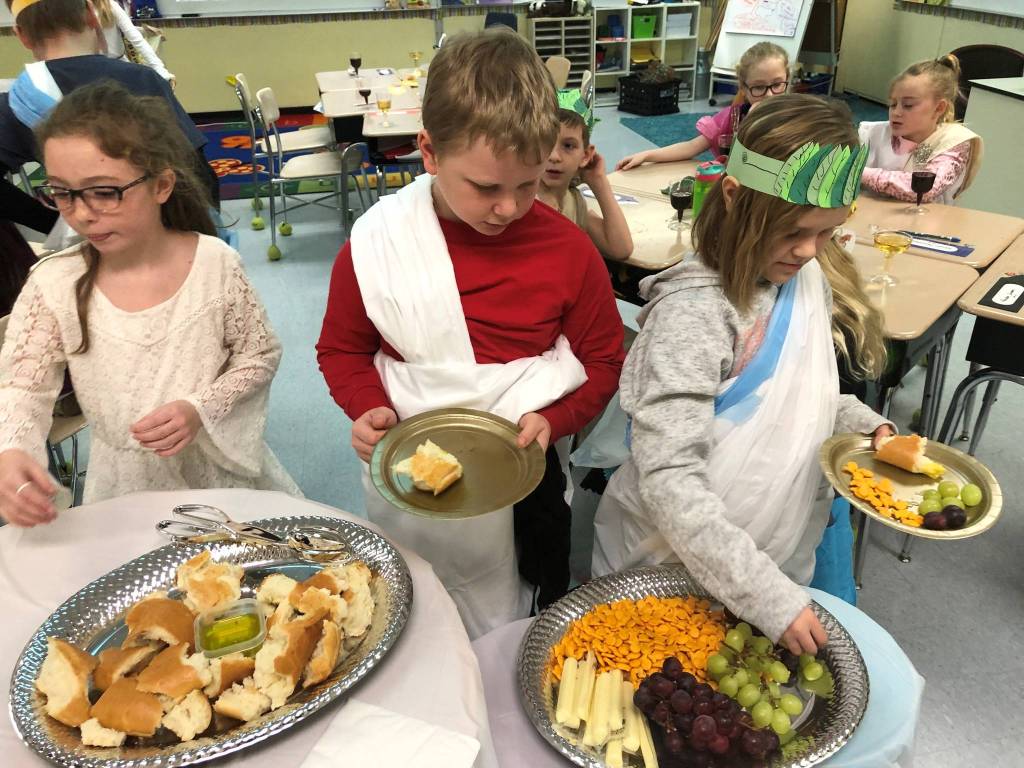 Third-graders (from left) McKenna Cox, Blake Arnold and Xyla Reichner prepare to feast on ancient Roman foods at the conclusion of their study unit. Photo by Robin Forrest