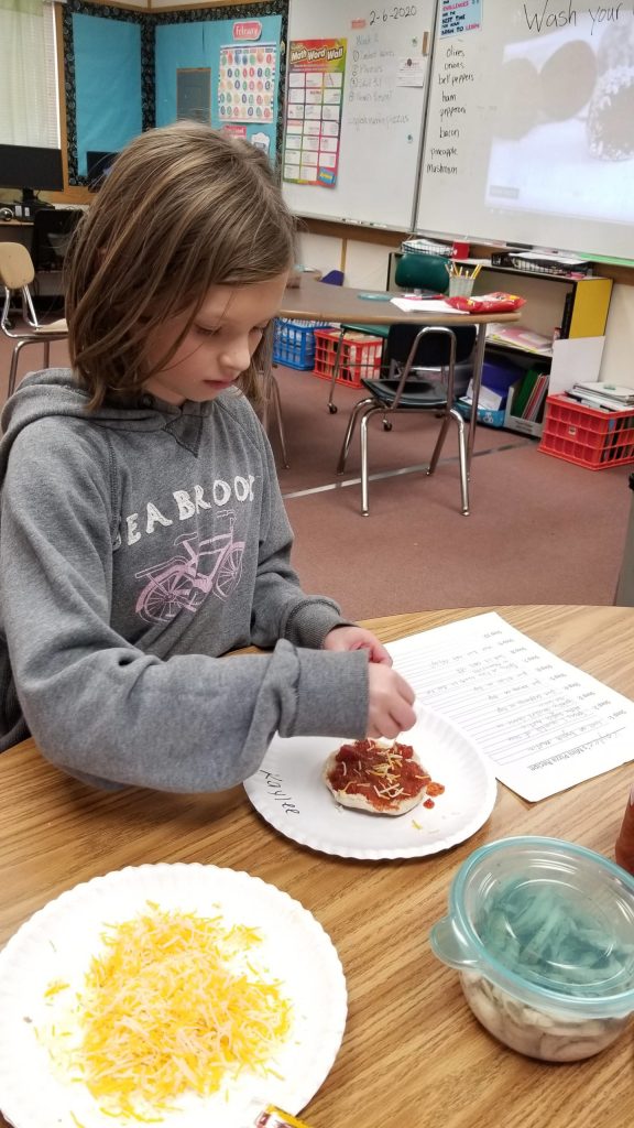 Kaylee Meyer follows the recipe she created for a mini pizza as part of a writing project. Photo by Melissa Sagara