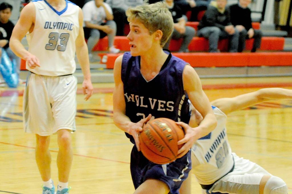 Wolves guard Erik Christiansen (center) drives towards the rim during the first quarter of Sequims 59-47 loss to the Olympic Trojans in an Olympic League tiebreaker game on Feb. 8 that meant the Trojans qualified for the district playoffs. Chrisiansen led the Wolves with 12 points. Sequim Gazette photo by Conor Dowley