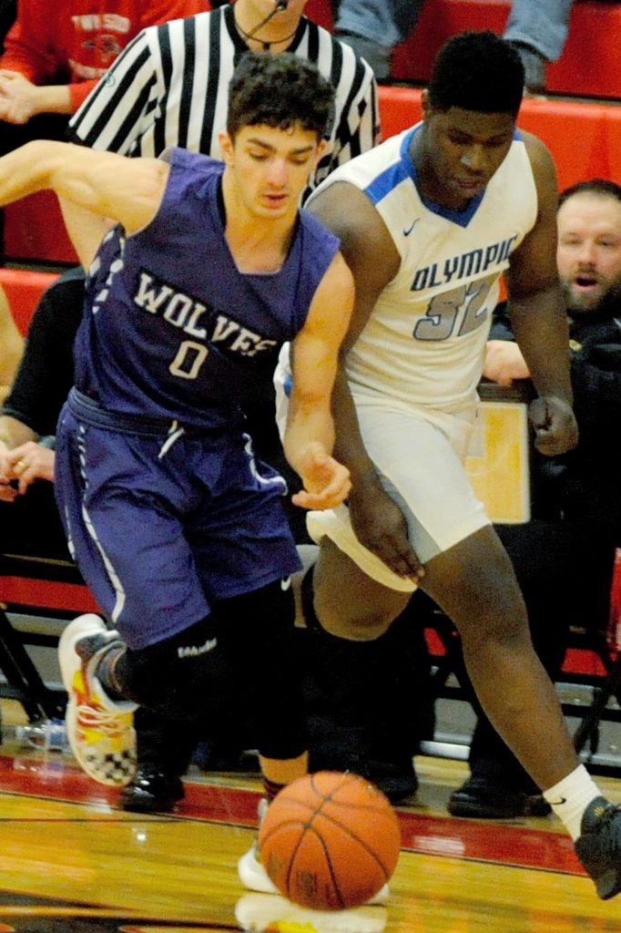Sequims Dallin Despain (0) fights to win a loose ball with Olympic Trojans forward Malcolm DeWalt in the second quarter of the Wolves 59-47 loss to the Trojans in an Olympic League tiebreaker game on Feb. 8 that sent the Trojans to the district playoffs. Sequim Gazette photo by Conor Dowley