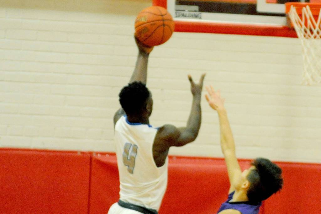 Olympic Trojans forward Malcolm DeWalt (4) goes up for a layup over Sequims Riley Chen (right) in an Olympic League tiebreaker on Feb. 8. The Wolves lost the game 59-47 in part because of struggling to contain DeWalt, and the Trojans are headed to the district playoffs. Sequim Gazette photo by Conor Dowley